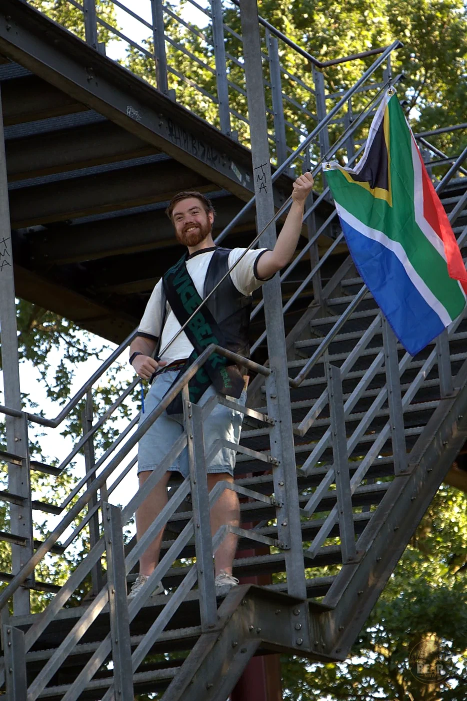 Joshua mit Schärpe und südafrikanischer Flagge an einer Stahltreppe